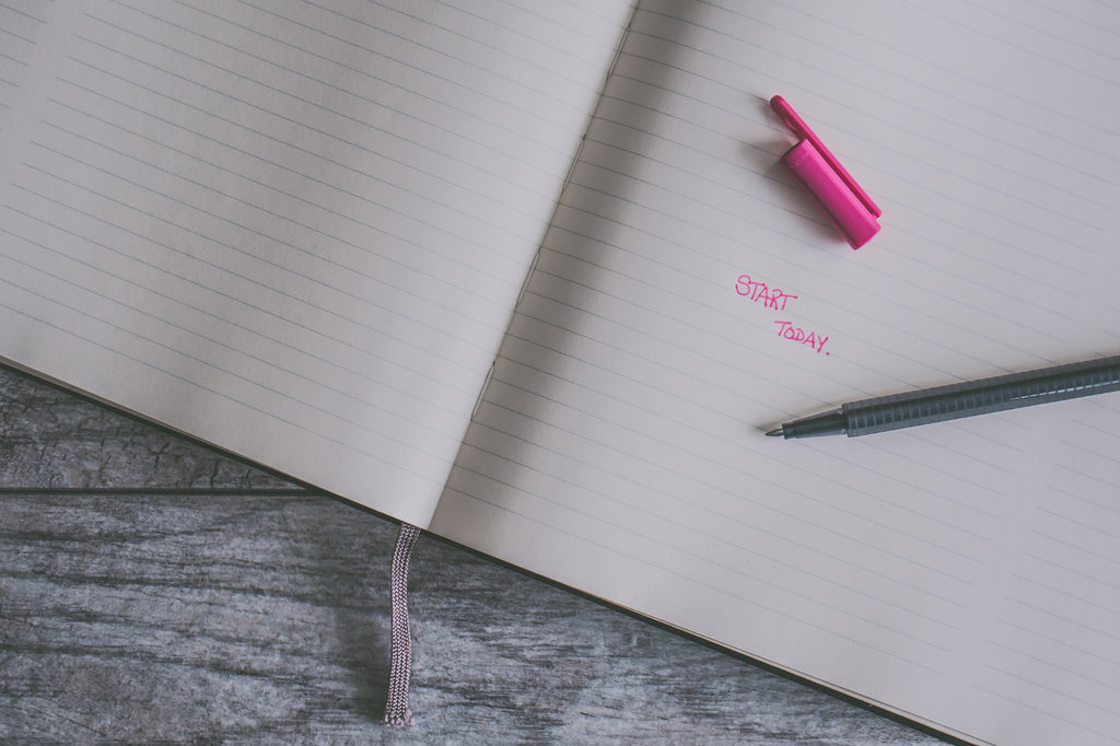 Capitalized text “start today” written in black pen on black line notebook.