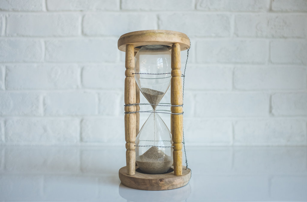 A flowing hourglass with sand almost completely in the lower bulb.