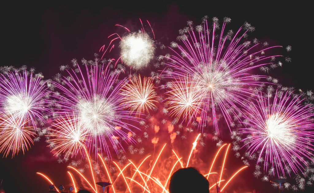 A silhouette of a person watching fireworks.