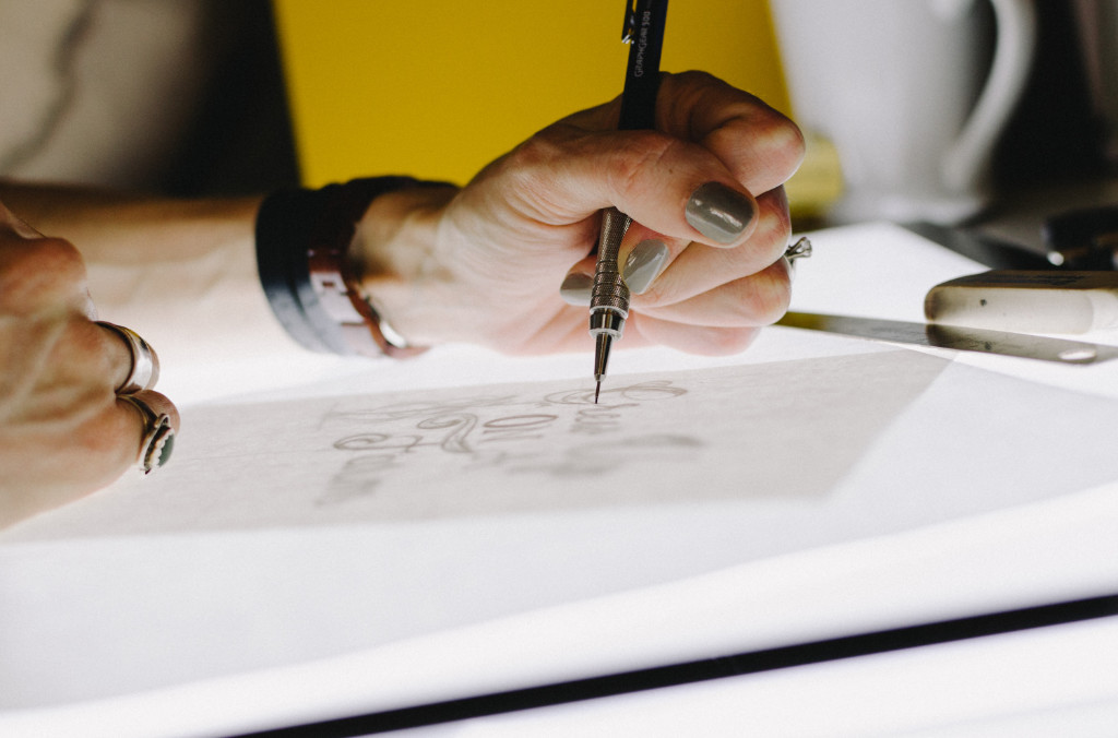 A person at a bright table drawing using a mechanical pencil.