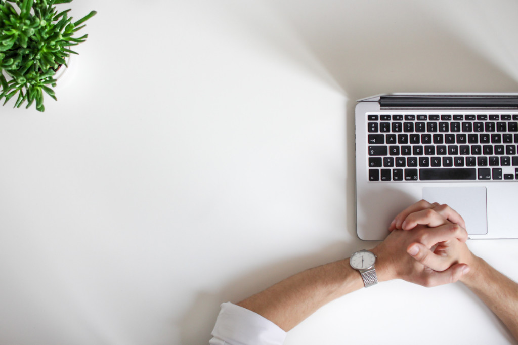 A person sitting idly in front of an open laptop.