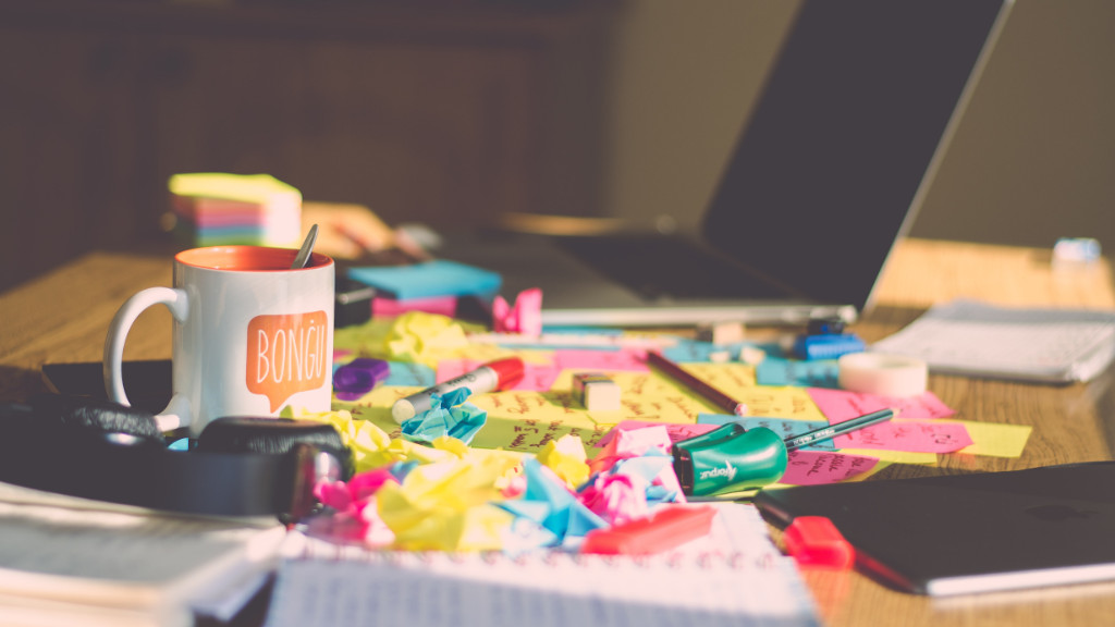 A messy desk with a laptop and a bunch of crumpled papers.