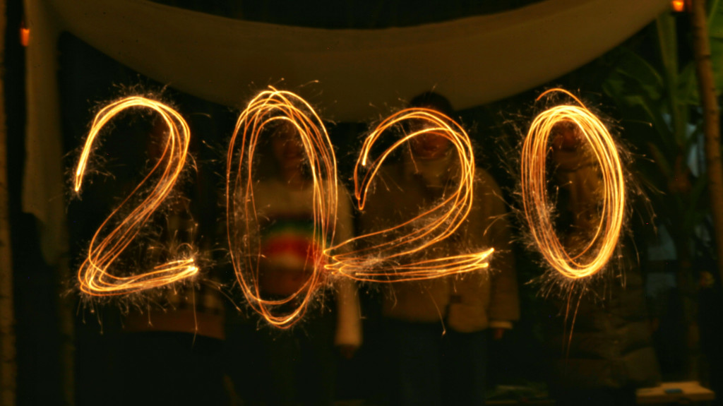 2020 written in light with people standing in the background.