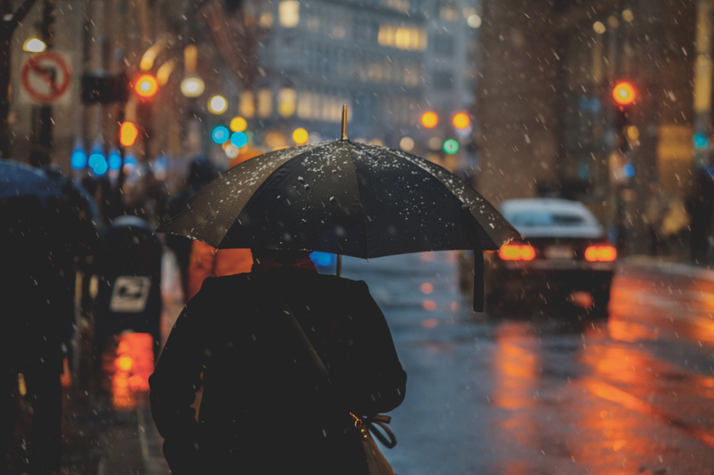 A person walking on a street in the rain, holding an umbrella.