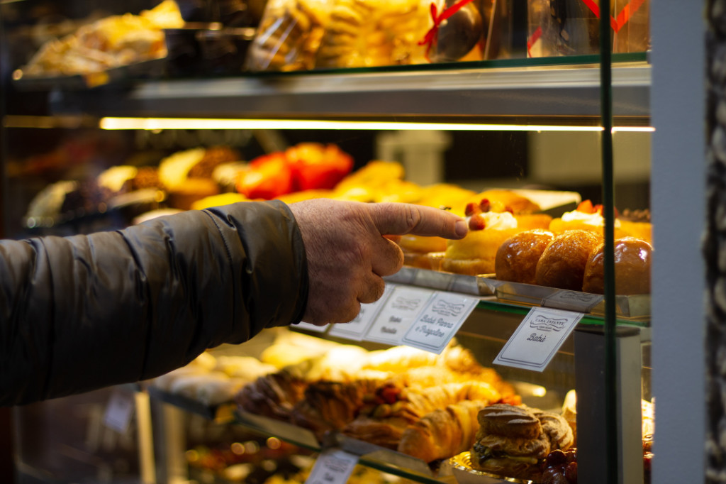 A person pointing to a wide selection of sweet pastries.